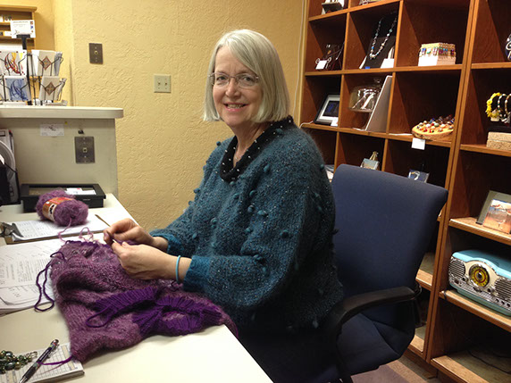 Textile artist Di Morgan works on a sweater while working her shift at the gallery.